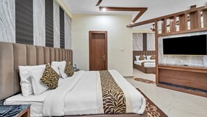 A modern hotel room with a large bed, a TV, and a ceiling fan. - Hotel Bhawani International (Reasi)