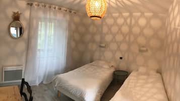Ein Schlafzimmer mit zwei Betten, einem runden Tisch, einem Spiegel und einer Deckenleuchte.
