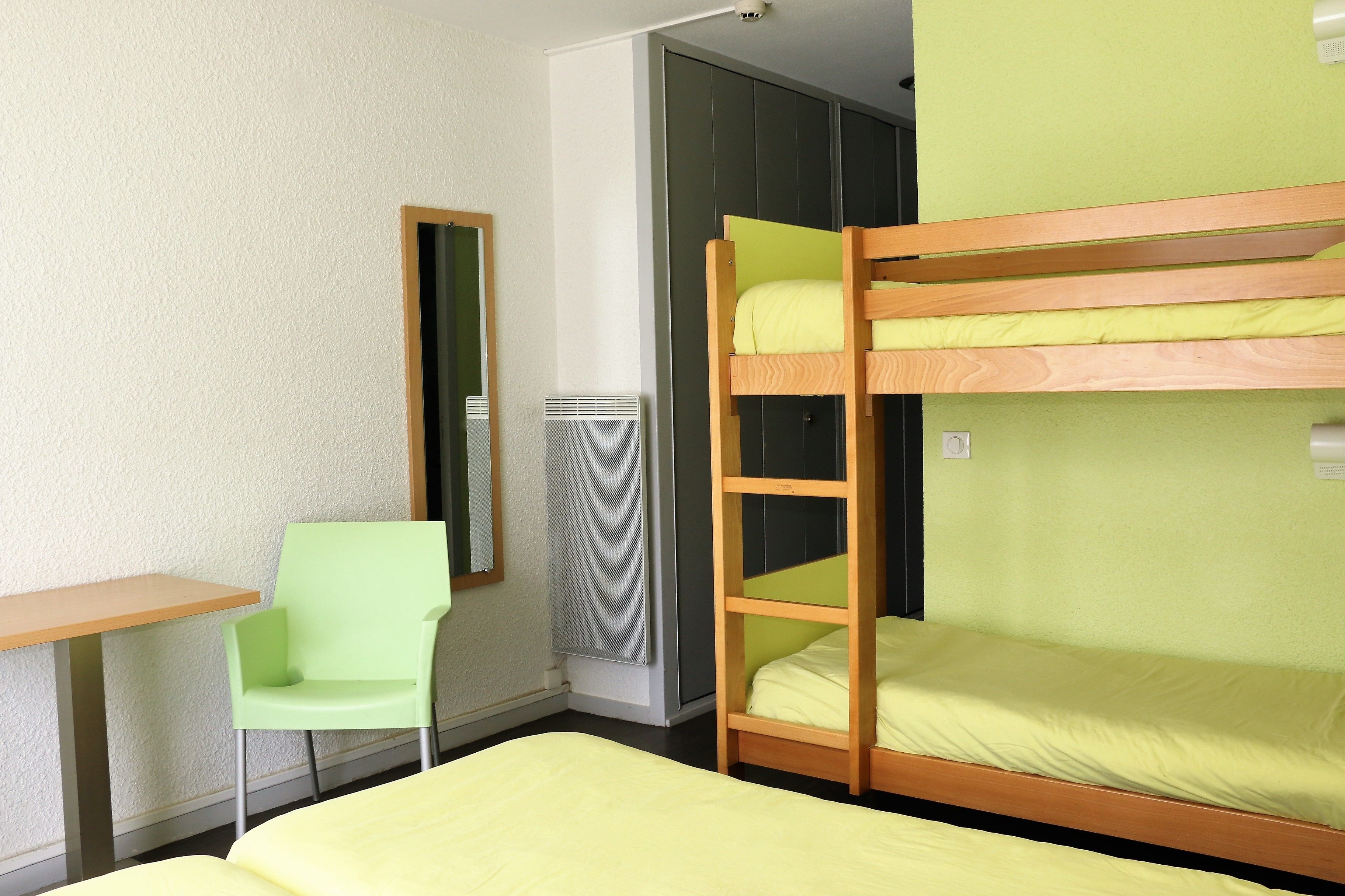 Une chambre avec des lits superposés, une chaise et une petite table.