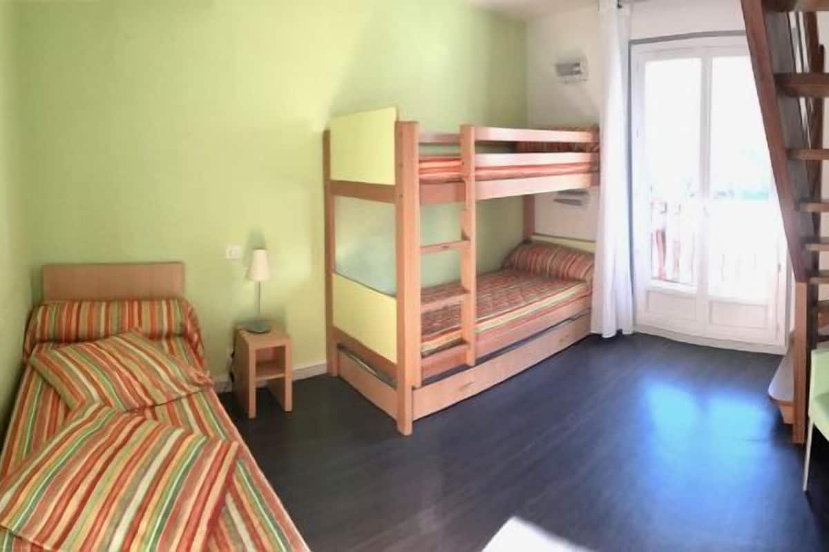 A room with bunk beds, a desk, a lamp, and a small table.