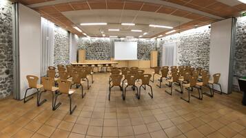 Ein Konferenzraum mit Steinwand, einer Whiteboard und mehreren in Reihen angeordneten Stühlen.