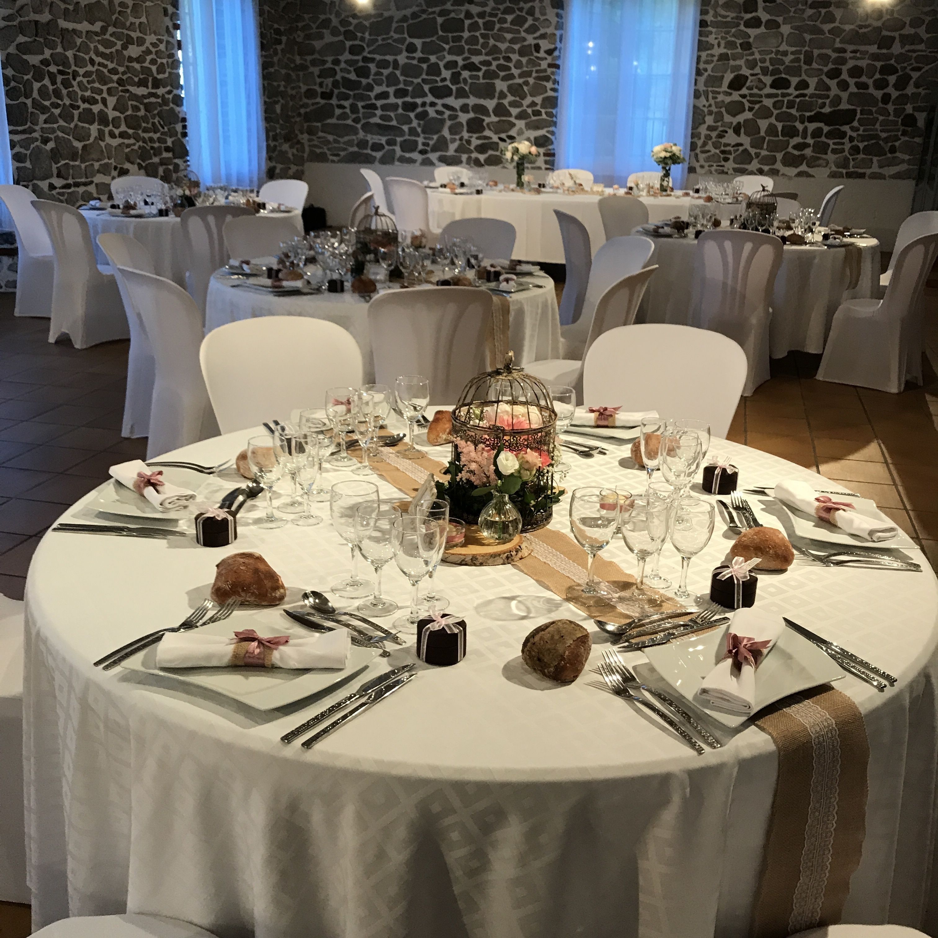 Un montaje formal para comedor con mesas redondas, manteles blancos y sillas.
