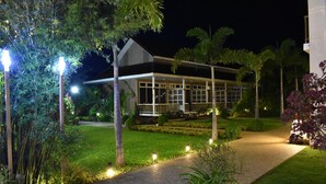 Ein modernes Gebäude mit Glasfassade und gepflegtem Gartenbereich mit Wegen und Beleuchtung.