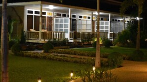 Ein Hotel mit überdachtem Außenbereich, mehreren Zimmern mit großen Fenstern und einem gepflegten Garten.