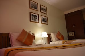 Una camera d'albergo con due letti, un comodino, una lampada e un armadio.
