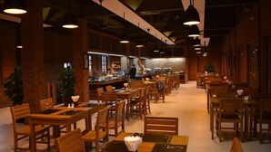 Ein geräumiges Restaurant mit Holztischen und -stühlen, einer Bar und Backsteinwänden.