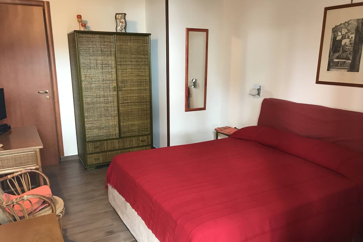Une chambre avec un grand lit, une armoire en bois, une petite table et une chaise.