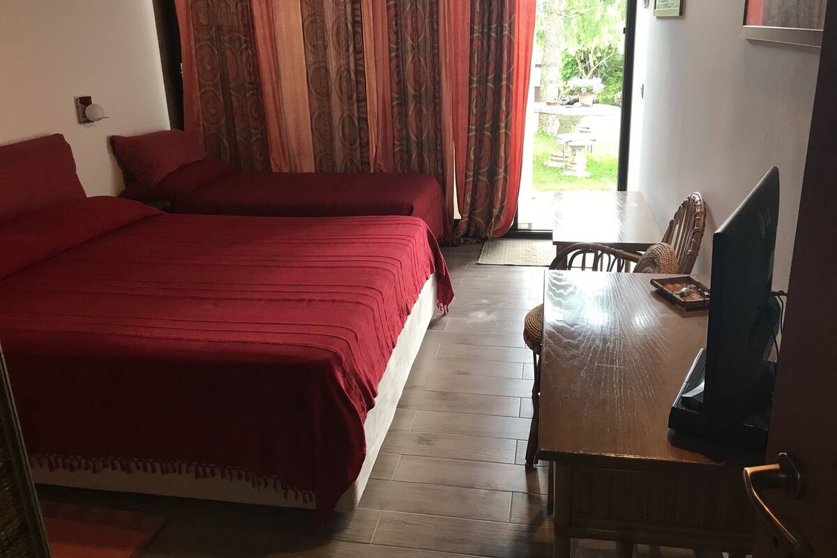 Une chambre avec deux lits, une table en bois, une chaise et un téléviseur.