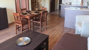 A modern kitchen with a central island, wooden dining table, and chairs. - HoliApart Gdanska 52 (Krynica Morska)