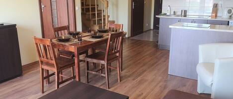 A modern kitchen with a central island, wooden dining table, and chairs.