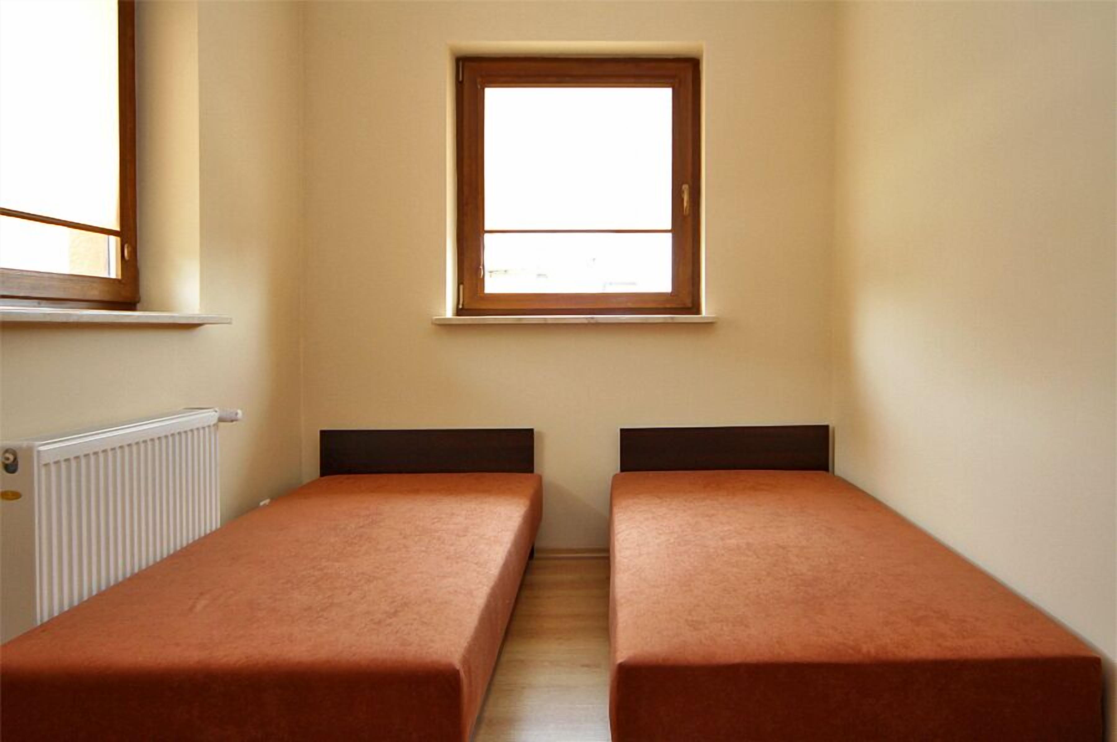 Une petite chambre individuelle avec deux lits simples, une fenêtre et un radiateur.