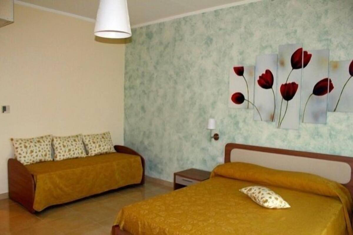 Une chambre avec deux lits, une lampe fixée au mur et une œuvre d’art à motifs floraux.
