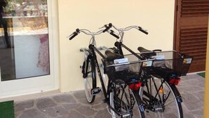 Two bicycles parked outside a building with a stone floor and a wooden door. - B&B La Sciuscitta (Morciano di Leuca)