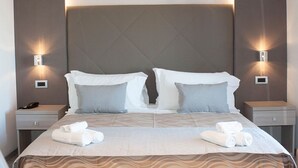 A hotel room with a large bed, two bedside tables, and wall-mounted lights. - Hotel Baby (Rimini)