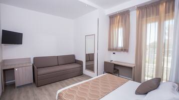 A modern hotel room with a bed, a sofa, a desk, and a TV.