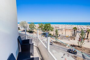 A balcony with a view of a beach and a road with vehicles.