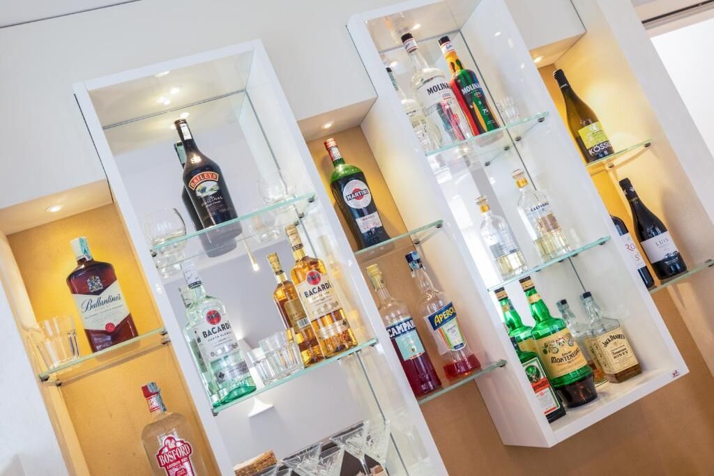 Un mueble bar con varios estantes que contienen diferentes botellas de licor.