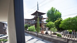 A traditional Japanese pagoda with a multi-tiered roof, surrounded by greenery and a stone wall. - Thanyaporn Hotel (Takayama)