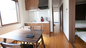 A compact kitchen with wooden cabinets, a black range hood, and a coffee maker on the counter. - Thanyaporn Hotel (Takayama)