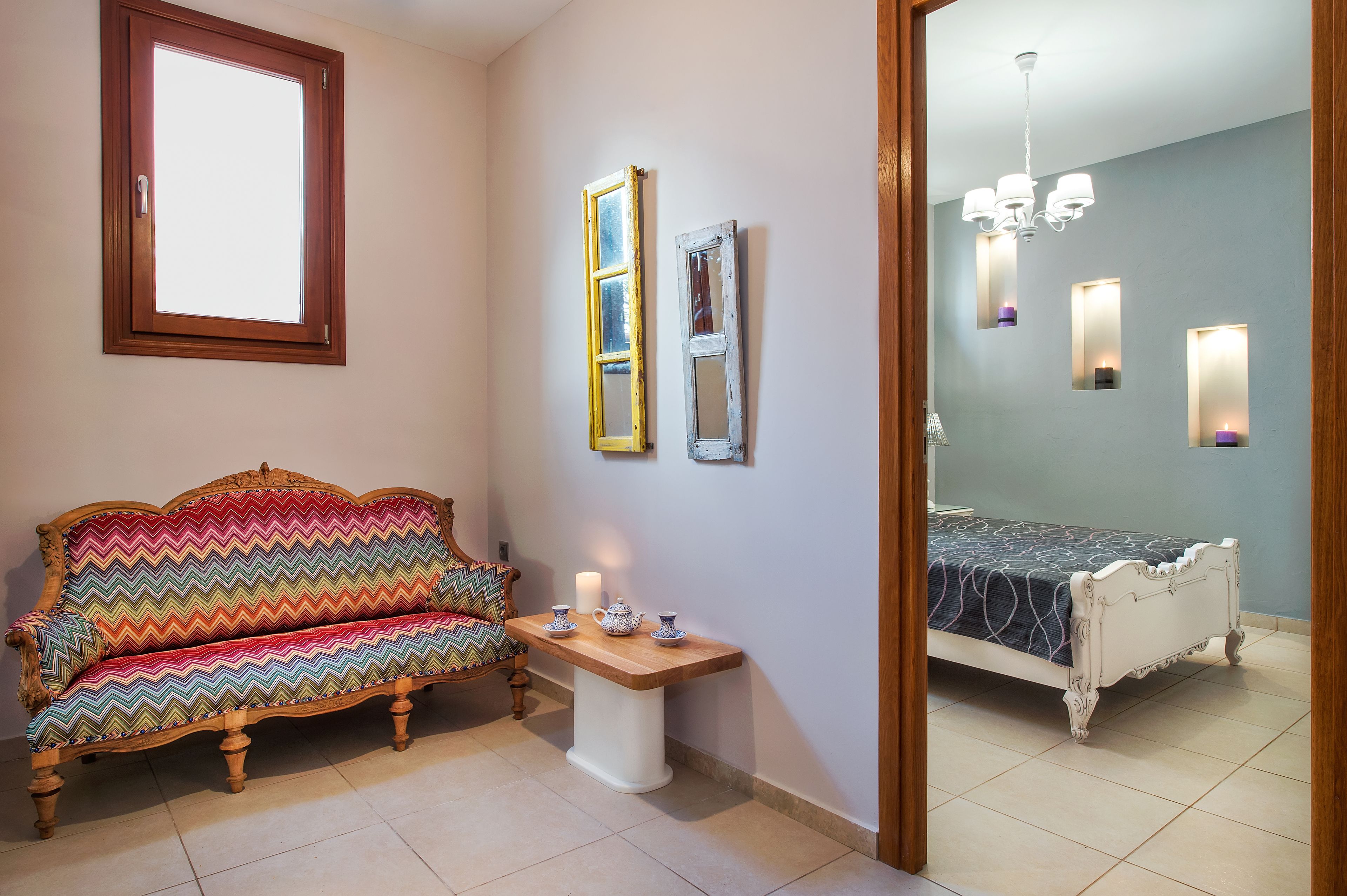 A room with a sofa, a small table with a candle, and a bed.