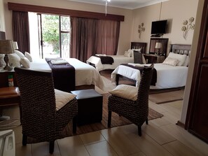 A hotel room with two beds, a sofa, a TV, and a lamp. - Gemstone Guest House (Klerksdorp)