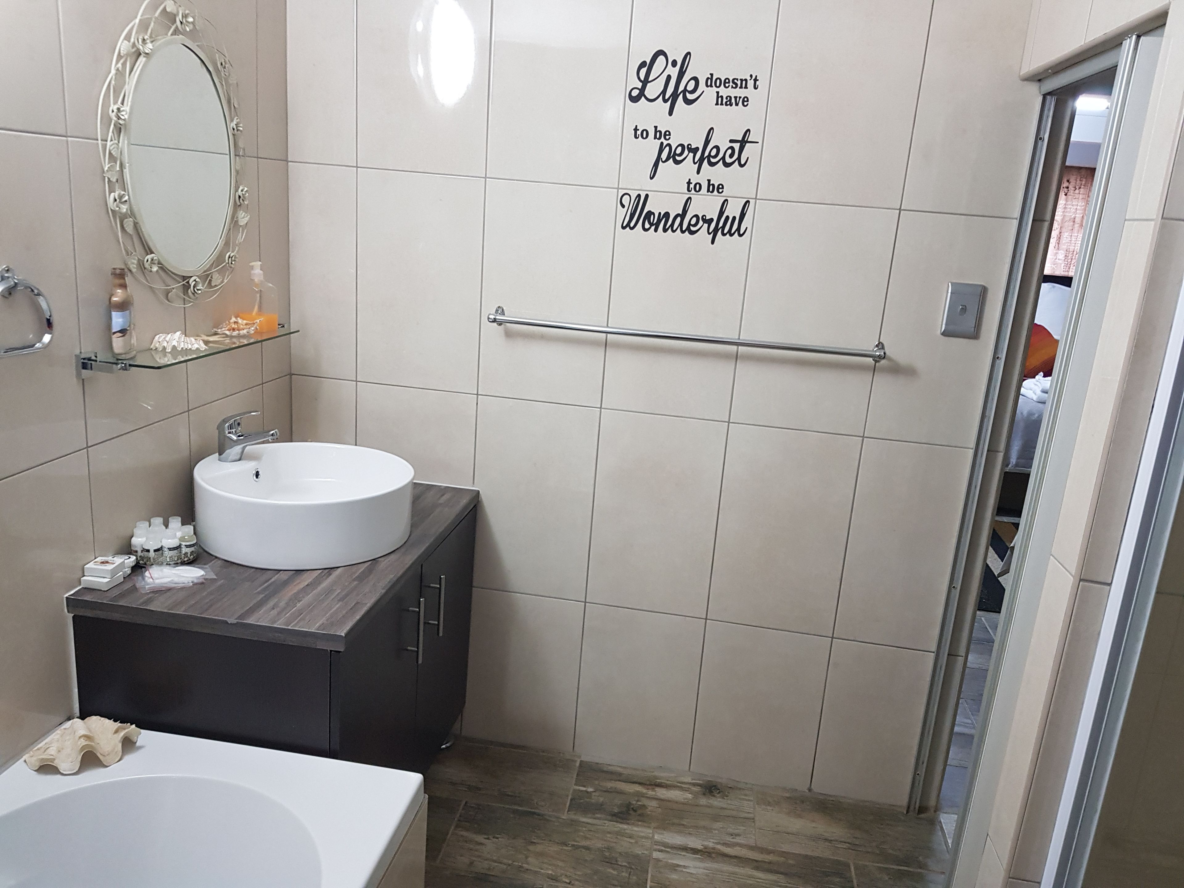 Een moderne badkamer met een ronde wastafel, een spiegel met decoratieve lijst en een handdoekhouder.