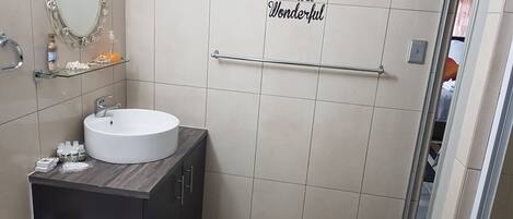 Een moderne badkamer met een ronde wastafel, een spiegel met decoratieve lijst en een handdoekhouder.