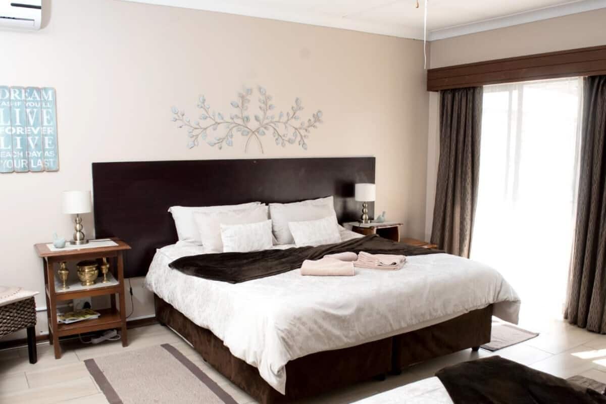 A bedroom with a large bed, bedside tables, a wall decoration, and a window with curtains.