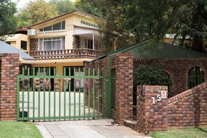A two-story house with a balcony, a brick gate, and a number 15 sign. - Gemstone Guest House (Klerksdorp)