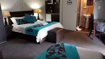 Habitación de hotel con cama, lámparas de noche, escritorio, silla, microondas, lavamanos y cartel de 'No Fumar'.
