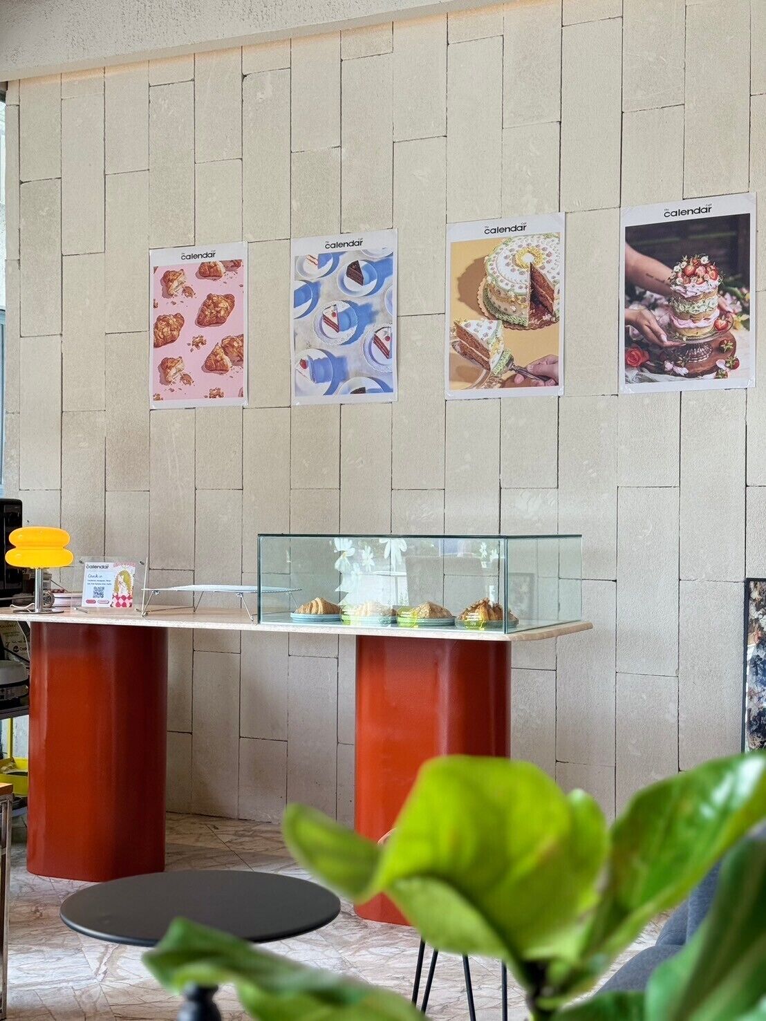 A reception area with a wooden wall, a glass display case with pastries, and a sign with the word 'calendar'.