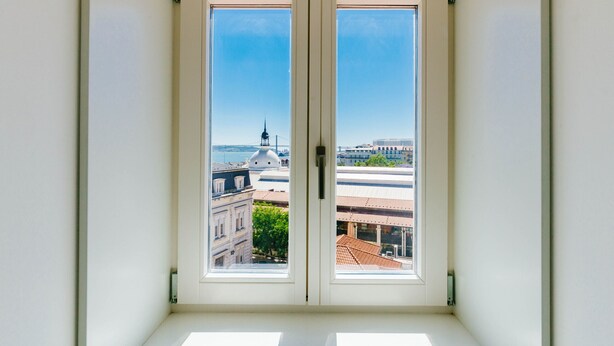 A room with a large window overlooking a cityscape, including a prominent dome and buildings. - Boho Studio (Lisboa ciudad)