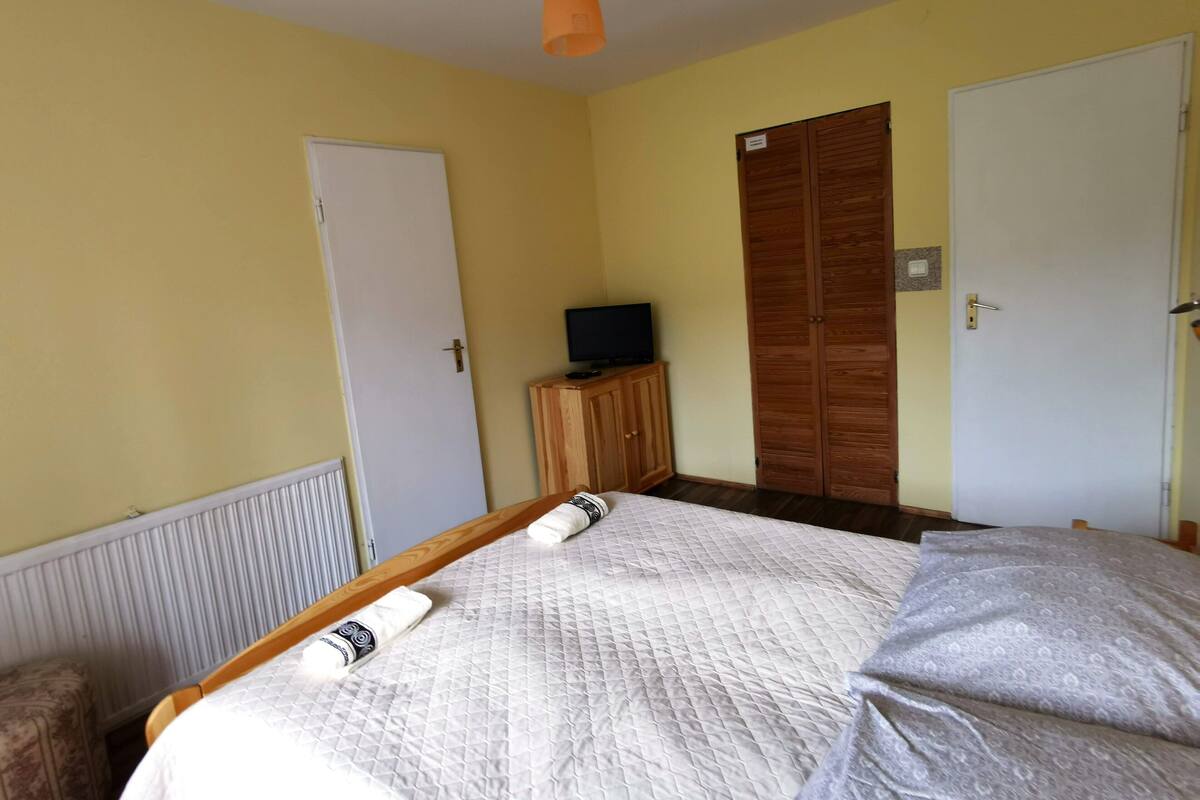 Ein Schlafzimmer mit Bett, Kleiderschrank, Fernseher und Heizkörper.