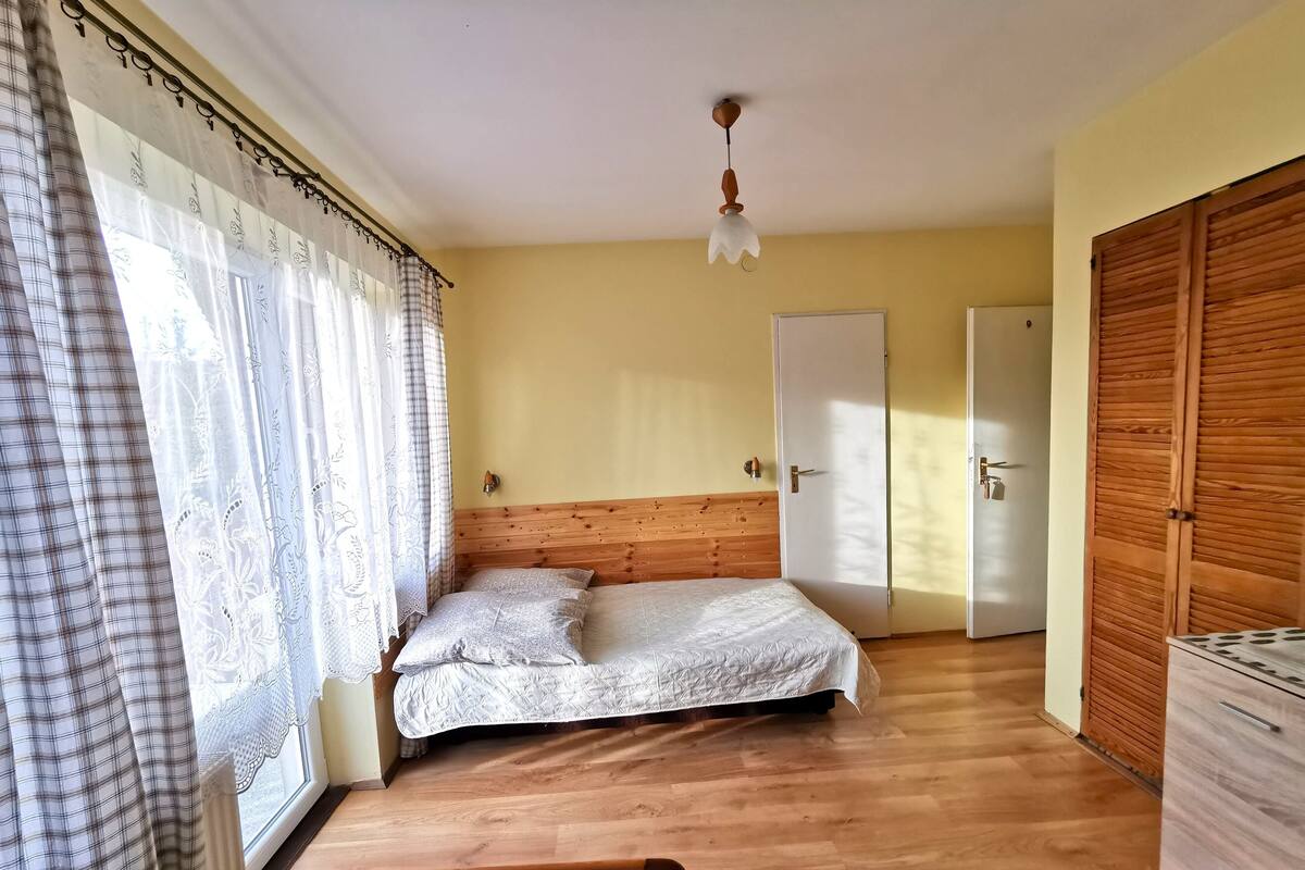 Ein Schlafzimmer mit einem Holzkopfteil, einem Bett mit gesteppter Bettdecke, einem Nachttisch und einem Kleiderschrank.