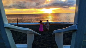 A beach scene with two people walking towards the sunset. - Pacific Buddies - Campsite (Dingalan)
