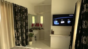 A modern hotel room with a bed, a TV on the wall, and a view into the kitchen area. - Pacific Buddies - Campsite (Dingalan)