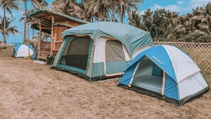 A campsite with several tents, including a large one with a mesh window and a smaller dome-shaped tent. - Pacific Buddies - Campsite (Dingalan)
