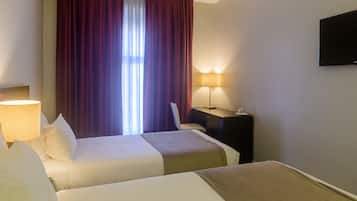 Une chambre d’hôtel avec deux lits, un bureau, une chaise, une télévision et une lampe.
