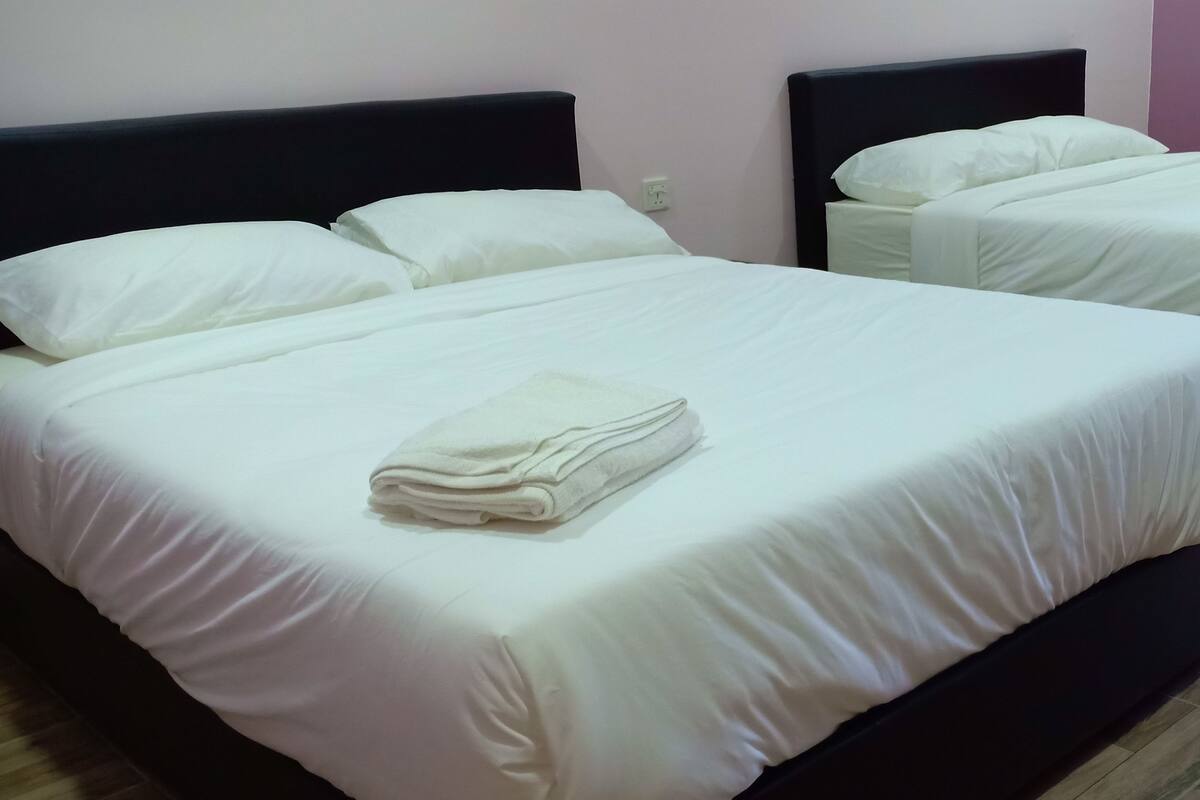 Ein Hotelzimmer mit zwei Betten, jeweils mit weißer Bettwäsche und Kissen, sowie einem gefalteten Handtuch auf dem Bett.