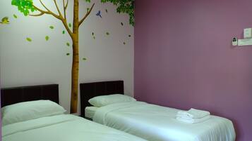 A hotel room with two beds, a tree decal on the wall, and a purple accent wall.