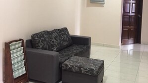 A living room with a sectional sofa, a wooden cabinet, and a door.