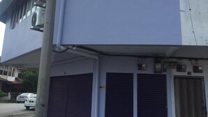 A building with a flat facade, large windows, and closed shutters.