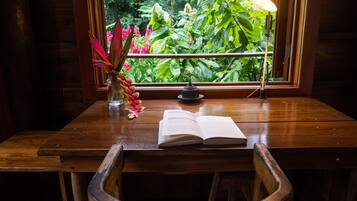 A wooden desk with a book, a lamp, and a vase with flowers.