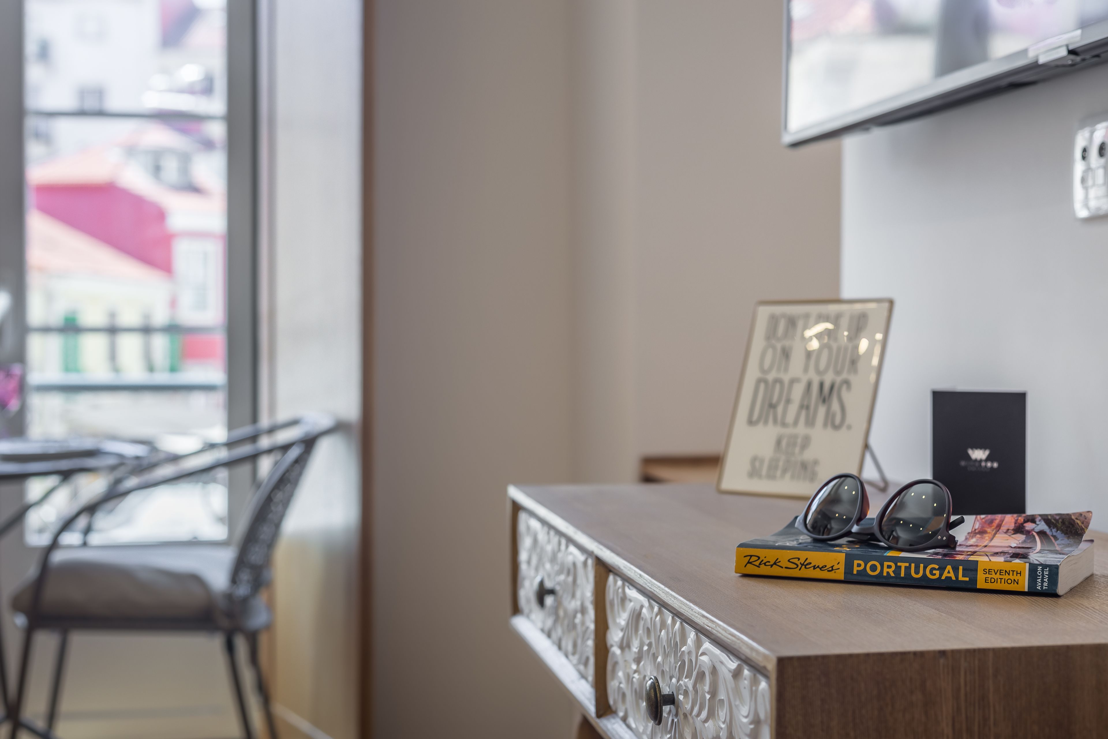 A wooden table with a book titled 'Portugal' and a pair of glasses on it.