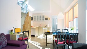 Un apartamento moderno con comedor, cocina y una escalera que sube a un nivel superior.