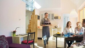 Una sala de estar moderna con comedor, una escalera y una cocina.