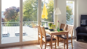 Un comedor con mesa y sillas, un paraguas amarillo y vistas al exterior.