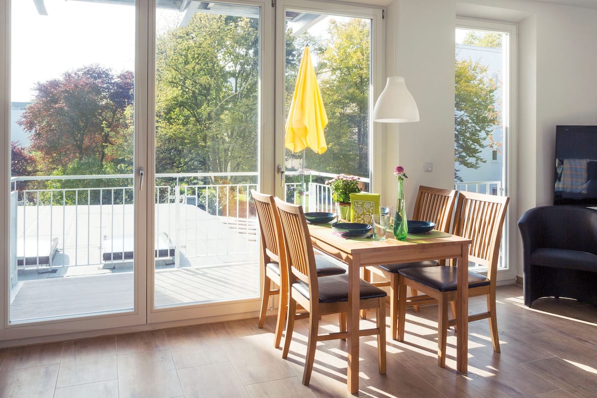 A dining area with a table and chairs, a yellow umbrella, and a view of the outdoors.