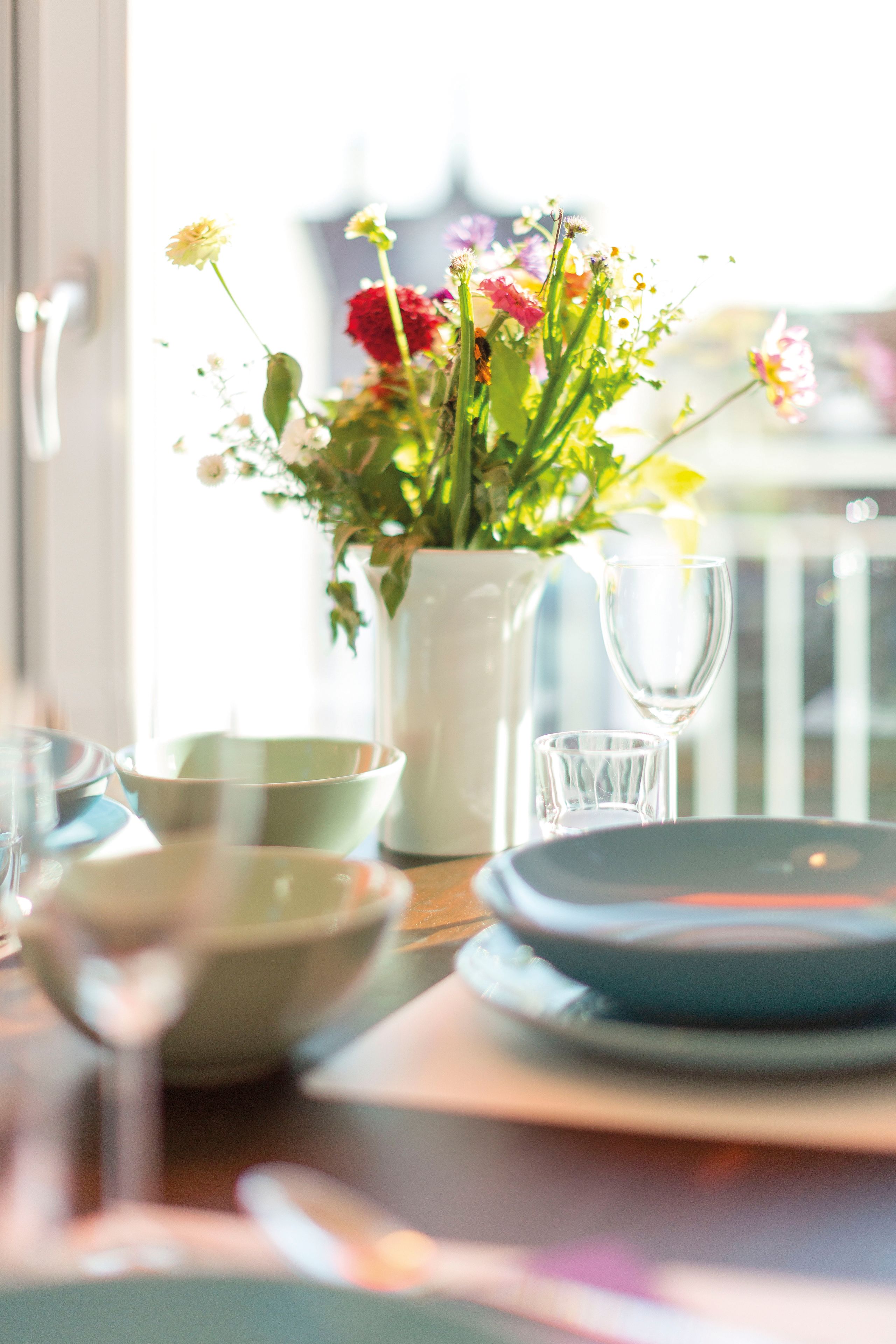 Ein Esstisch mit einer Blumenvase, einem Glas und Schalen.