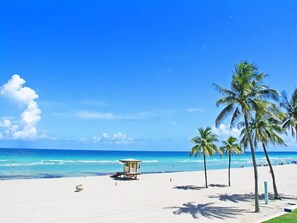 A beach with a lifeguard tower, palm trees, and a clear blue sky. - Amazing Apartment,hallandale Beach, Walk to Ocean! (Hallandale Beach)